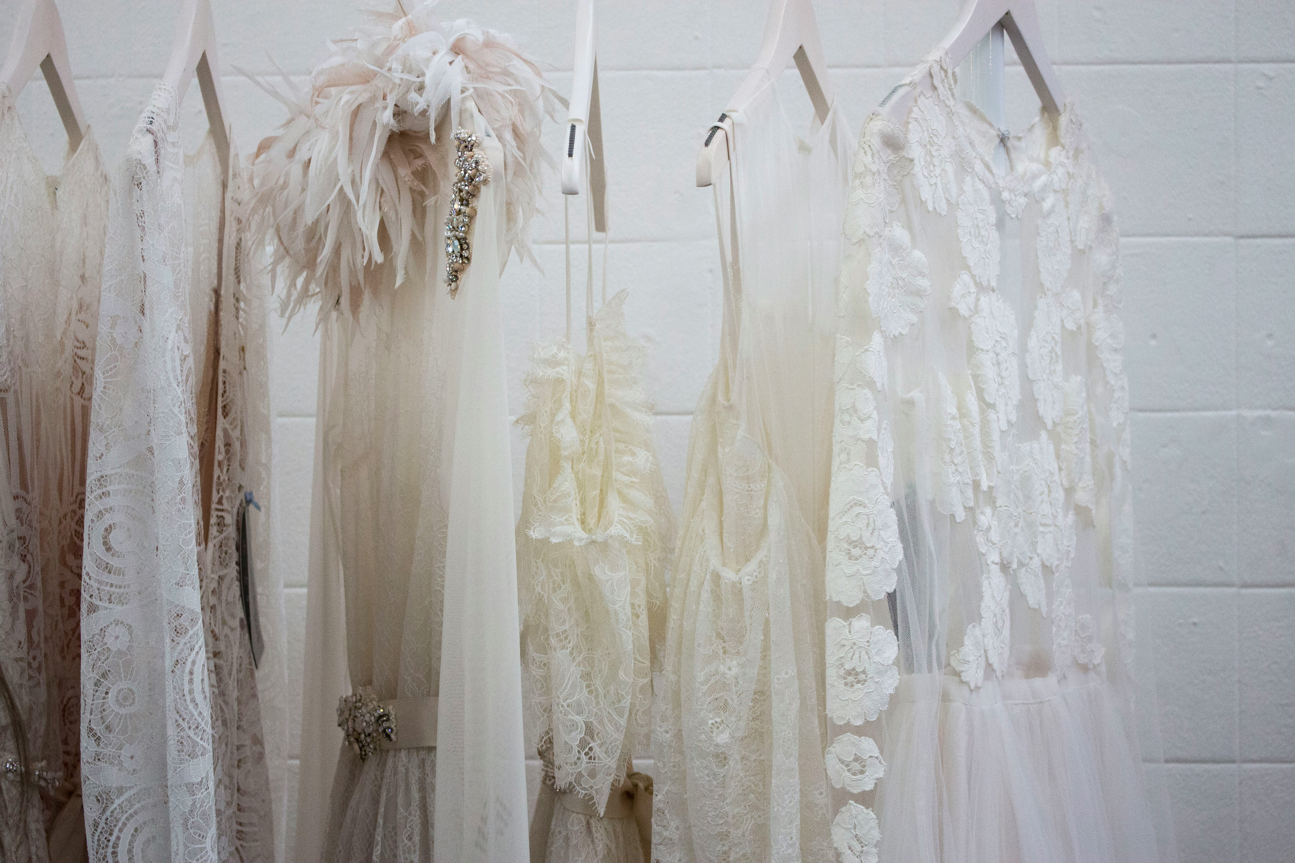 six women's white dresses hanging on hangers